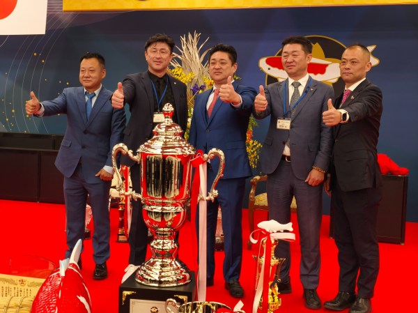ผู้ร่วมงานถ่ายภาพกับถ้วยรางวัลบนเวที All Japan Koi Show 2026