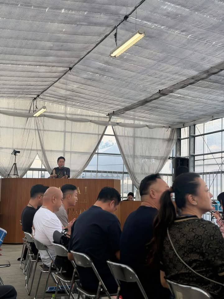 ผู้เข้าร่วมงานนั่งเรียงแถวภายในโรงเรือนประมูล
